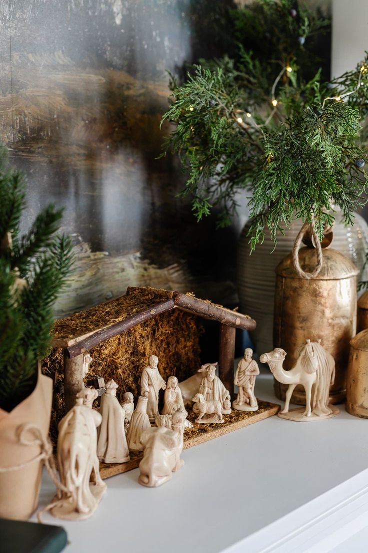 a nativity scene with figurines on a mantle next to a christmas tree