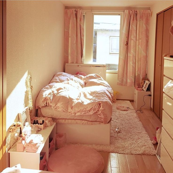 a bedroom with a bed, dresser and window in the corner is lit by sunlight coming through the window