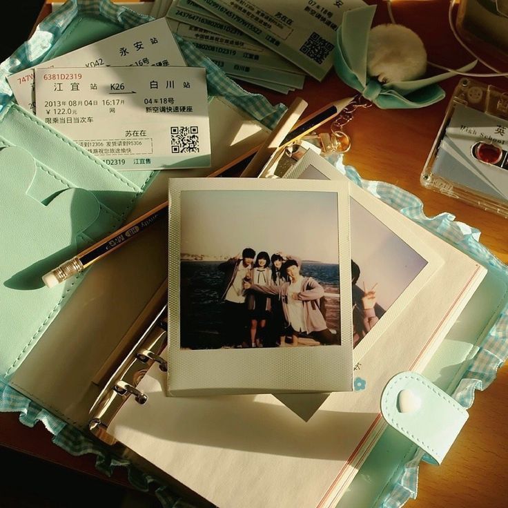 a table topped with photos and papers on top of a wooden table next to a pair of scissors