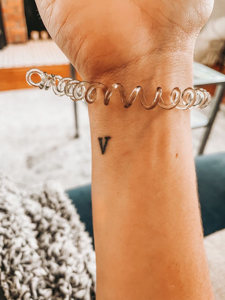 a woman's arm with a tattoo on it and a chain around the wrist