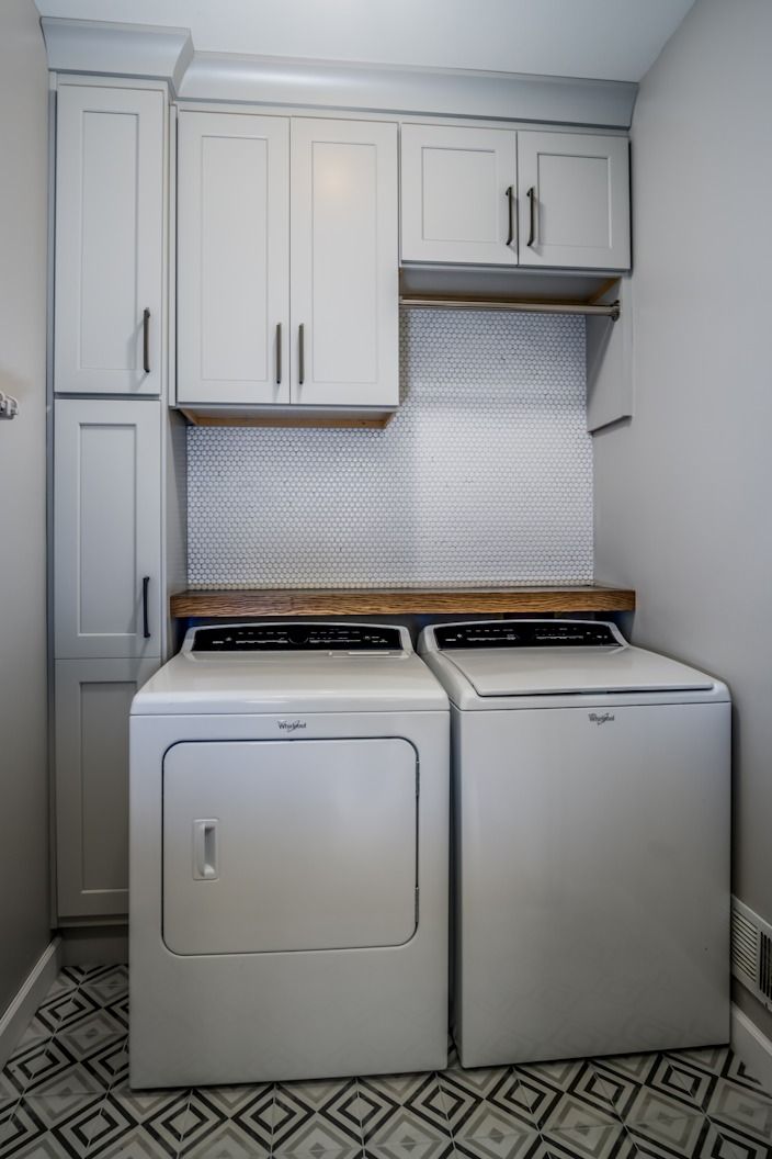 a white washer and dryer in a small room with cabinets on the wall