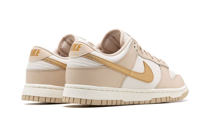 The Women’s Nike Dunk Low “Phantom/Metallic Gold” is a women’s-exclusive colorway of the classic low-top shoe with a premium-looking design.  In the “Phantom/Metallic Gold” rendition, Nike updates the retro basketball shoe with a white leather construction with Phantom-colored leather overlays.  A Metallic Gold leather Swoosh appears on the sides and gold “Nike” branding is embroidered on the heel.  Additional gold accenting includes a “Nike” logo on the tongue.  A Sail midsole and Phantom rubbe Gold Swoosh Dunks Outfit, Womens Dunk Low, Metallic Gold Shoes, Pop Shoes, Adidas Sl 72, Dunks Low, Gold Nike, Nike X Travis Scott, Ugg Ultra Mini