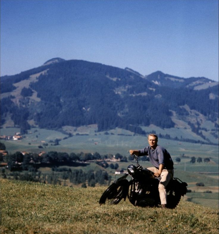 a man sitting on top of a motorcycle in the mountains