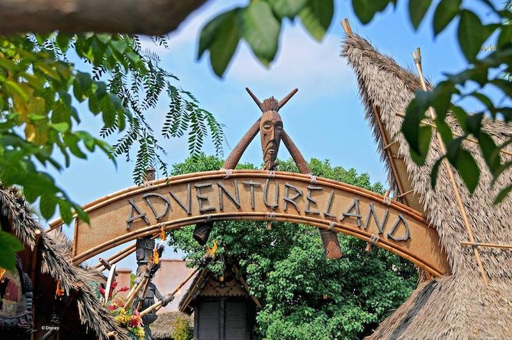 the entrance to an amusement park with a wooden sign that says adventureland on it