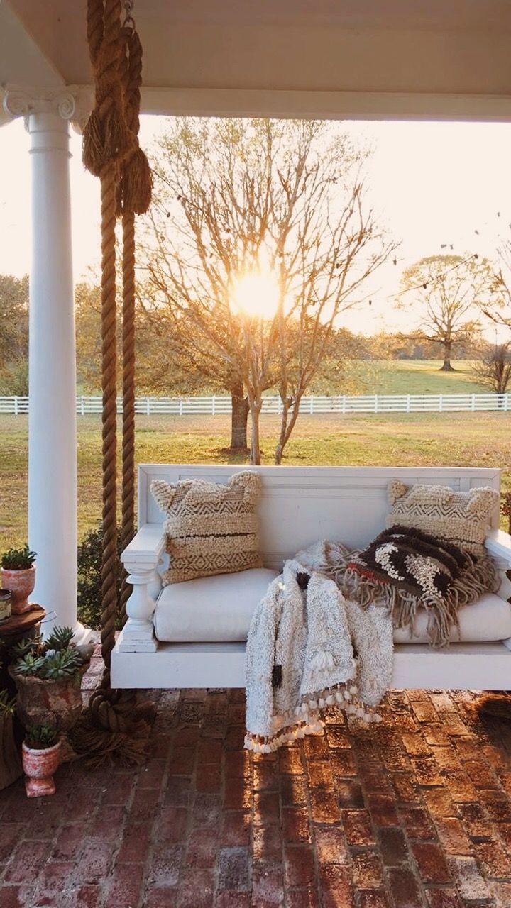 a porch swing with pillows and blankets on it