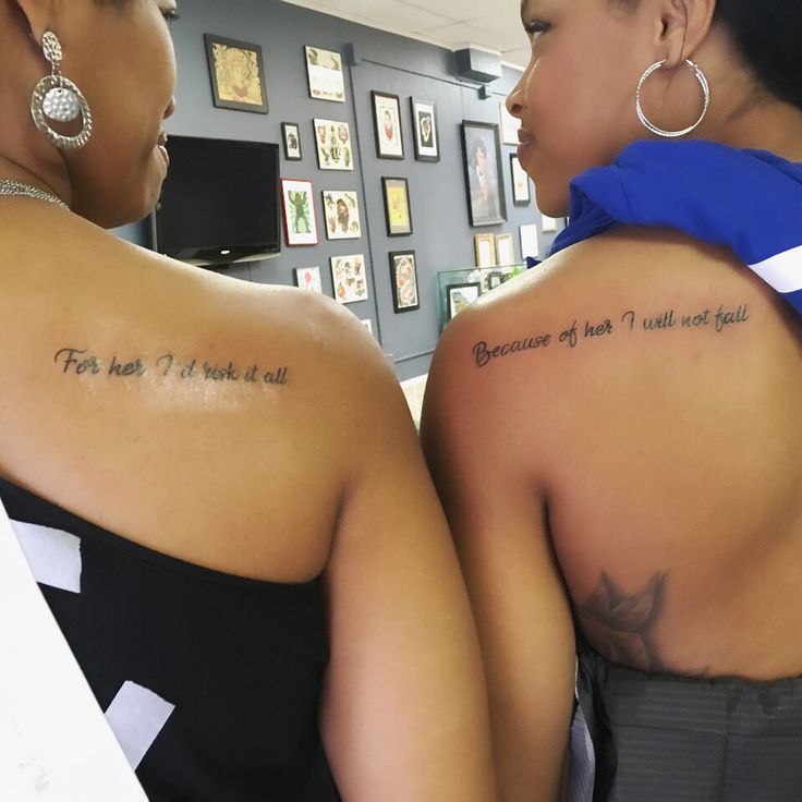 two women with tattoos on their backs looking at each other