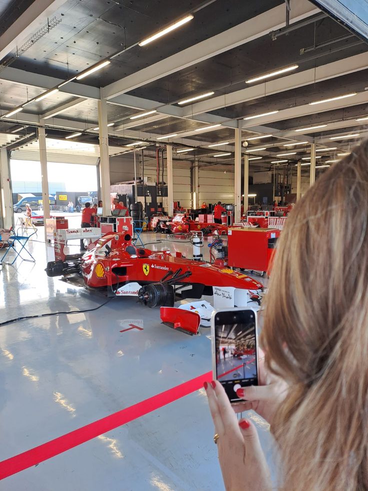 a woman taking a photo of the inside of a building with red equipment on display