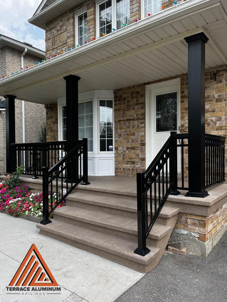 a front porch with black railing and flowers