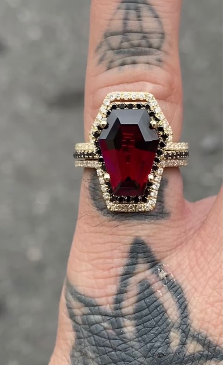 a woman's hand with a ring on it and a red stone in the middle