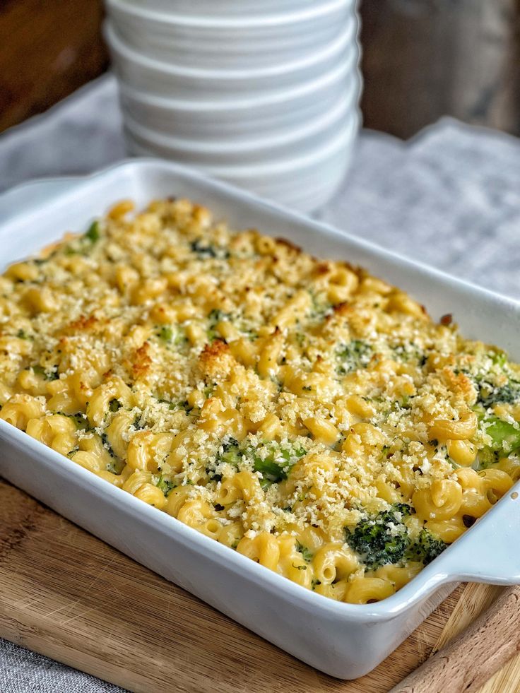 a casserole dish with broccoli and cheese in it on a cutting board