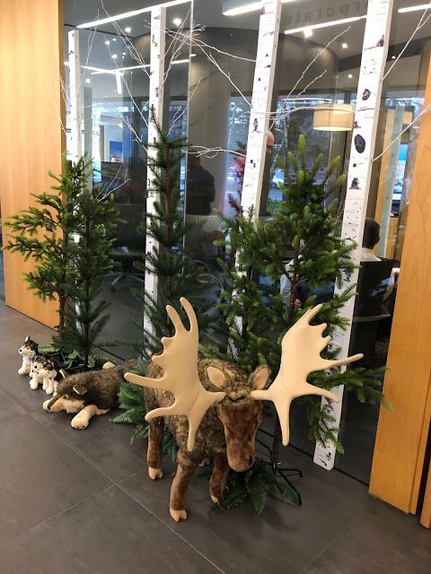 two moose statues are sitting in front of some christmas trees and other decorations on the floor