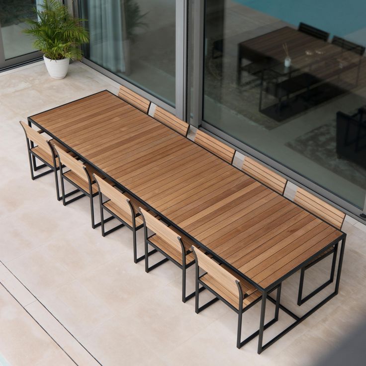 a wooden table with six benches next to an open glass window on the outside of a building