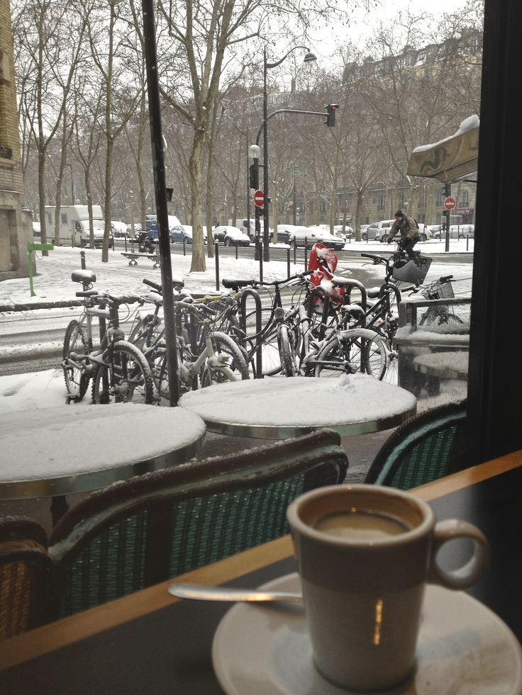 a cup of coffee sitting on top of a saucer next to a window covered in snow