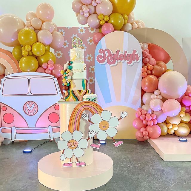 a birthday party with balloons, cake and flowers on the table in front of a vw camper van