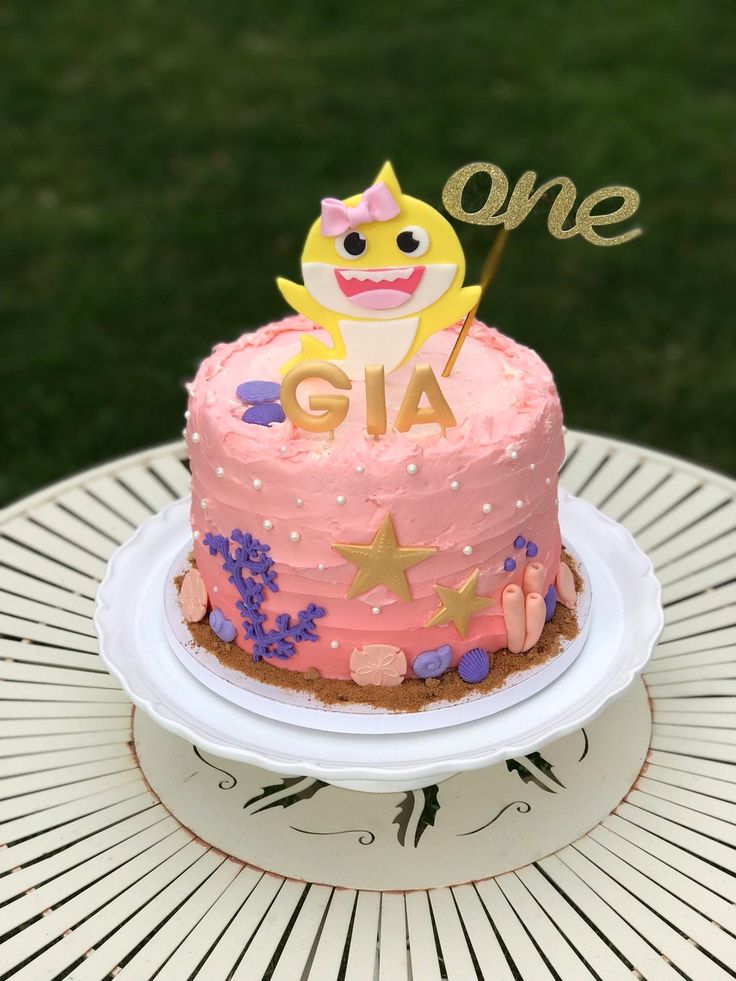 a pink cake sitting on top of a white plate covered in frosting and decorations