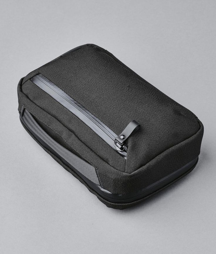 an empty black bag with zippers on the inside and side pockets, sitting on a gray surface