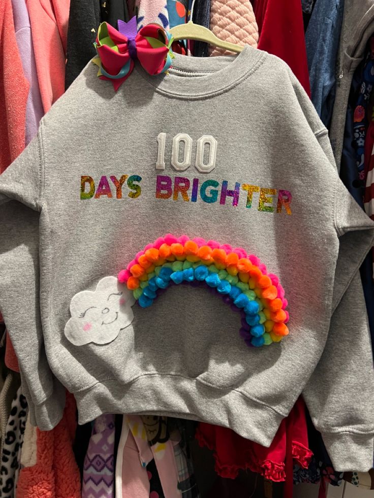 a sweatshirt with the words 100 days brighter written on it and a rainbow colored hair clip