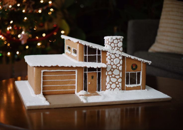 a gingerbread house on a table with a christmas tree in the background