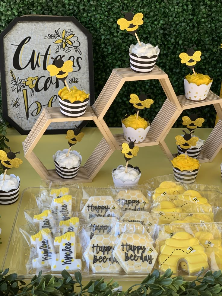 a table topped with cupcakes covered in yellow frosting and decorated like bees