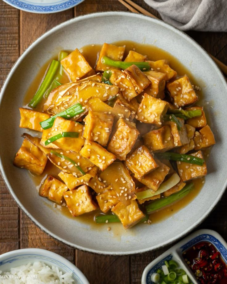 tofu with sesame seeds and green beans served in a white bowl on a wooden table