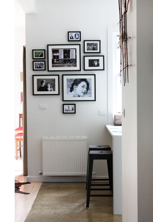 a white room with pictures on the wall and a stool in front of an open door