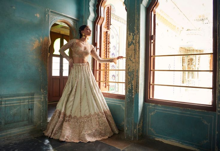 A stunning off-white lehenga with a gold embroidered blouse and skirt bottom.From Bindani’s Rang Mahal collection DELIVERY TIMEPlease allow 8-12 weeks for your outfit to arrive. FABRIC DETAILSHabutai silk Professional cleaning only. White Lehenga Choli, Lehenga And Blouse, White Lehenga, Green Suit, Change Image, Silk Lehenga, Net Dupatta, 12 Weeks, Off White Color