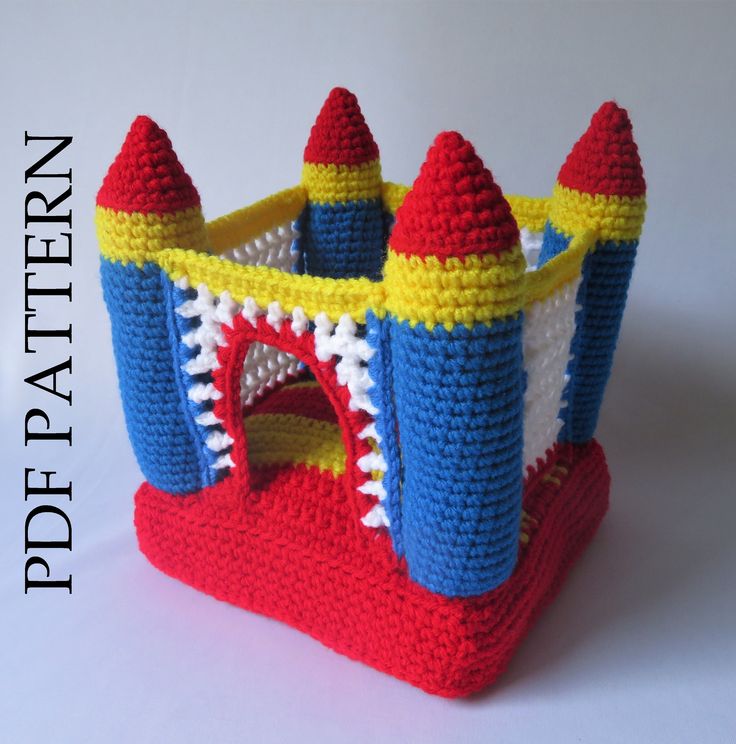 a crocheted toy castle sits on a white surface