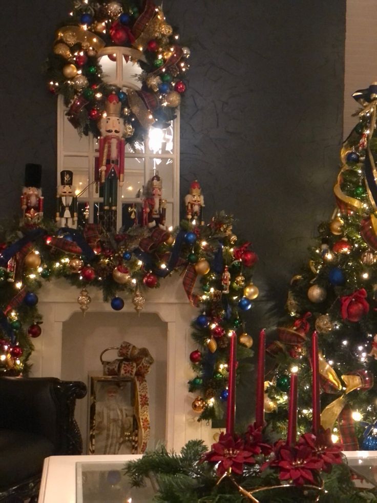 two christmas trees in front of a fireplace decorated with lights and garlands on the mantle