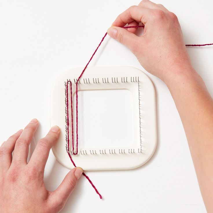 two hands are working on a piece of crafting material with yarn and scissors next to it