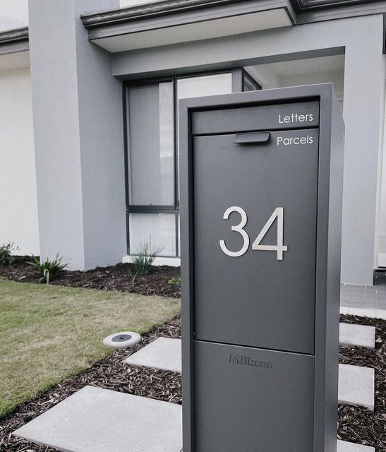 a mailbox sitting in front of a house with the number 34 on it's side