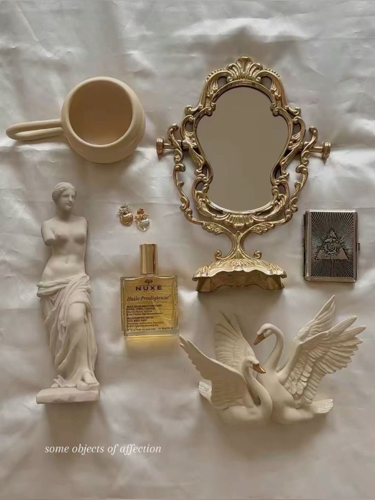 there are many items on the table including a mirror, swan statue and perfume bottle