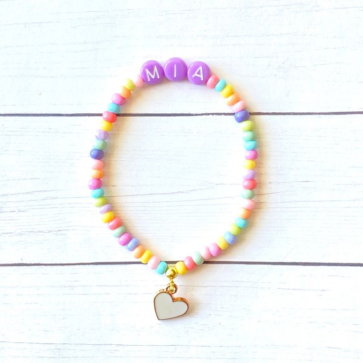 This is such a cute custom gift! You can customize it with any word or name! Each bracelet comes with a white heart charm and purple letter beads! 💜 The colorful czech beads are so adorable. The bracelets are beautifully packaged and ready to gift. Receipts are never included. If you want to include a special note, please let me know in the comments. Roll, don't pull. To avoid excess stretching please roll the bracelet on and off. Treat and store the bracelets gently. Sizing options are just a Personalized Friendship Bracelet For Birthday, Birthday Heart Charm Bracelet, Cute Customizable Charm Bracelet For Gifts, Playful Personalized Bracelets For Birthday, Playful Personalized Beaded Bracelets For Gifts, Playful Personalized Charm Bracelet For Birthday, Cute Custom Name Friendship Bracelets For Birthdays, Cute Custom Name Friendship Bracelets For Birthday, Personalized Multicolor Charm Bracelet For Gift