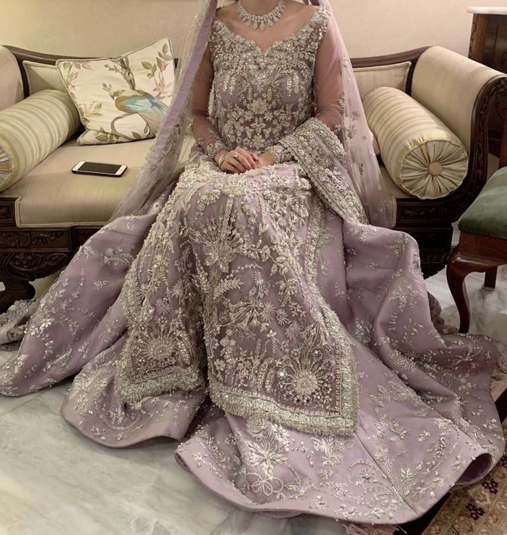 a woman sitting on top of a couch wearing a purple dress and headpieces