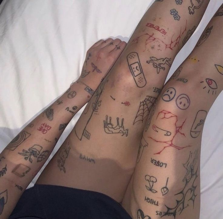 two people laying in bed with tattoos on their legs