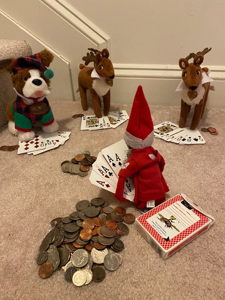 three stuffed animals sitting on the floor next to some cards and coins