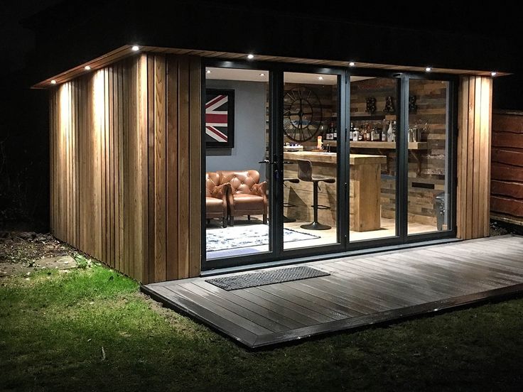 a small wooden shed sitting on top of a grass covered field next to a bar