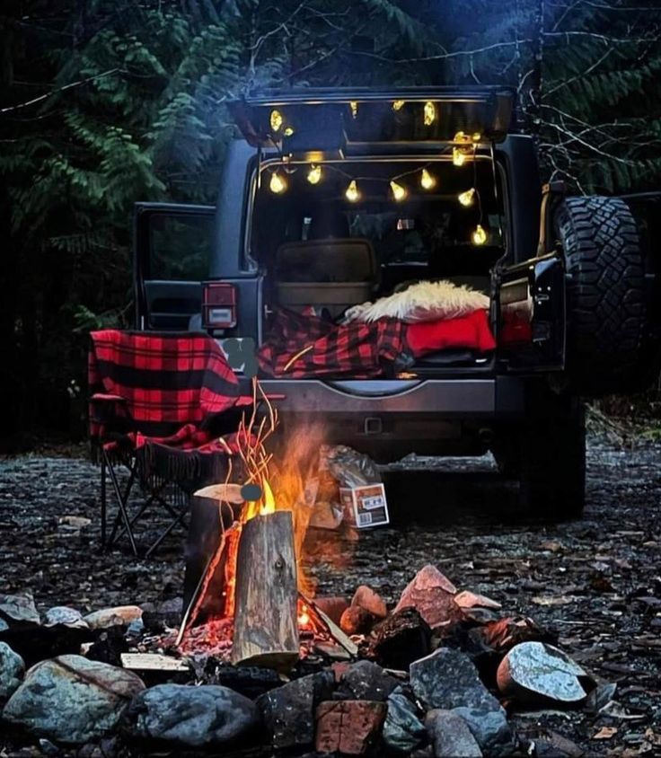 a camper van is parked next to a fire in the woods