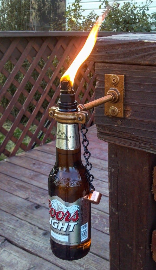 a bottle that is on top of a wooden table with a lighter in it's mouth