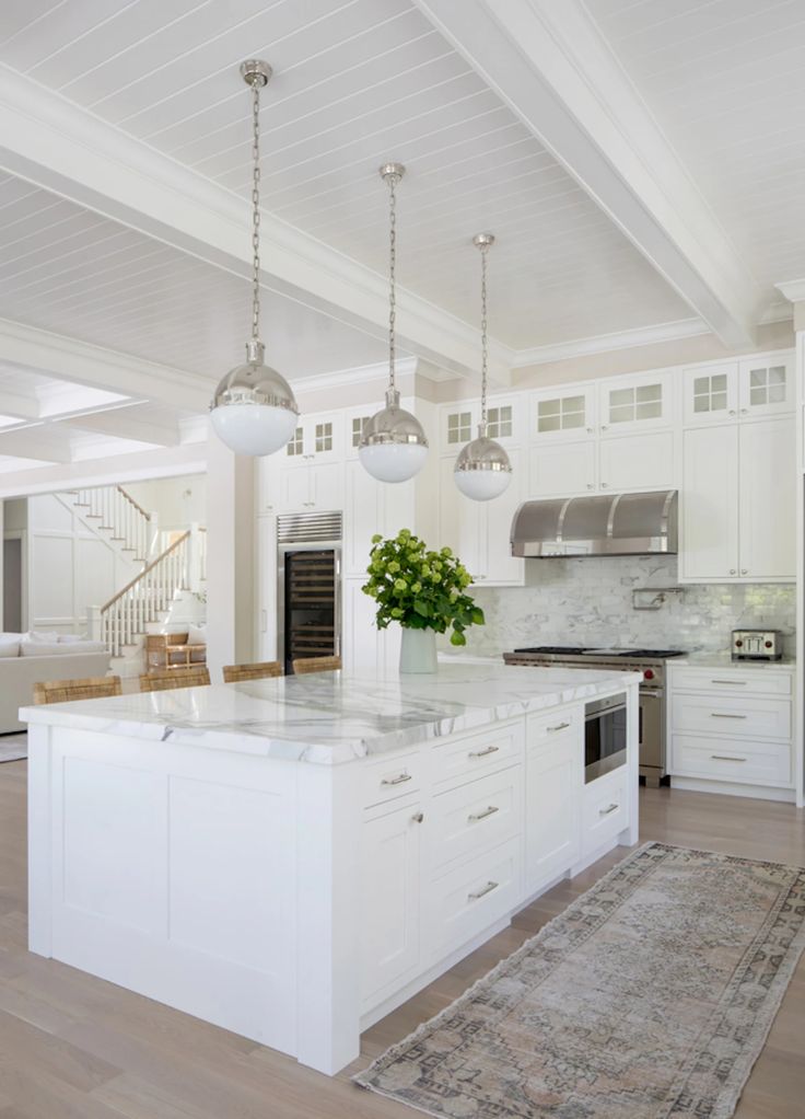 a large kitchen with white cabinets and an island in front of a stove top oven