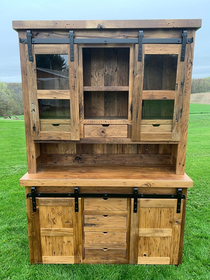 a large wooden cabinet sitting on top of a lush green field