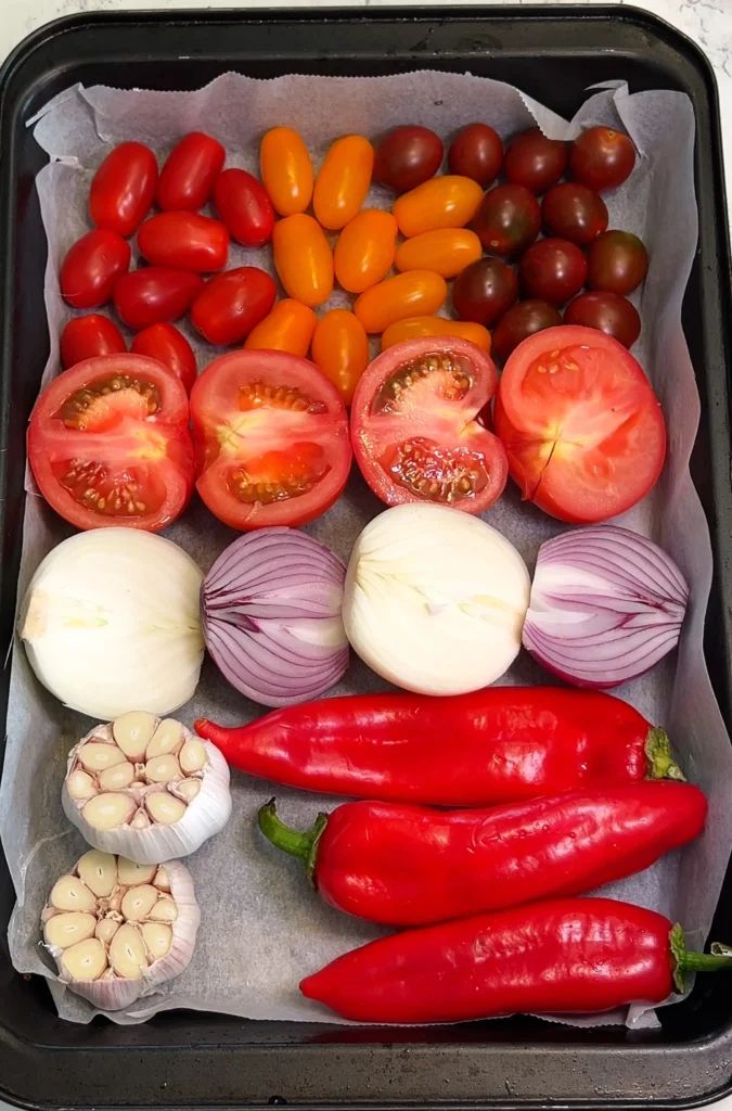 tomatoes, onions, peppers, and garlic are in a black tray on the counter