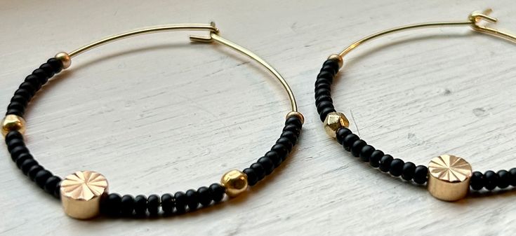 Introducing our vibrant Boho Seed Bead Hoop Earrings, the perfect blend of bohemian charm and contemporary style, featuring delicate gold-colored hoops with elegant, sleek black Czech glass seed beads paired with metallic gold beds with a carved golden sun centerpiece. Our Boho Seed Bead Hoop Earrings are also incredibly lightweight, ensuring optimal comfort. Whether you're heading to a music festival, a beach getaway, or simply want to add a pop of color to your everyday ensemble, these earring Adjustable Hoop Earrings With Black Beads, Adjustable Black Beaded Hoop Earrings, Adjustable Gold Bead Hoop Jewelry, Adjustable Hoop Jewelry With Gold Beads, Adjustable Hoop Earrings With Gold Beads As Gift, Adjustable Gold Beads Hoop Earrings As Gift, Adjustable Gold Beaded Hoop Earrings As Gift, Adjustable Black Beaded Hoop Jewelry, Gold Small Hoop Beaded Earrings For Festival