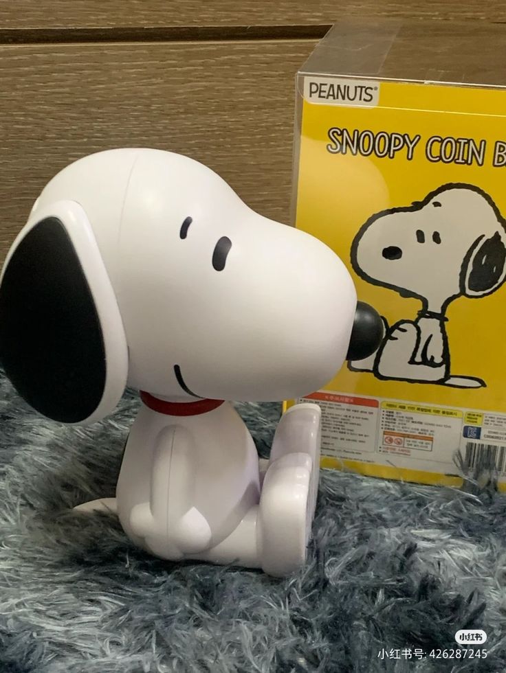 a snoopy coin bank sitting next to a book