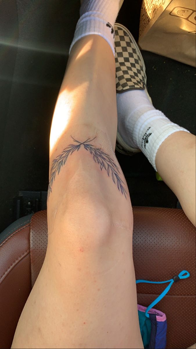 a person sitting in the back seat of a car with their legs crossed and tattoos on them