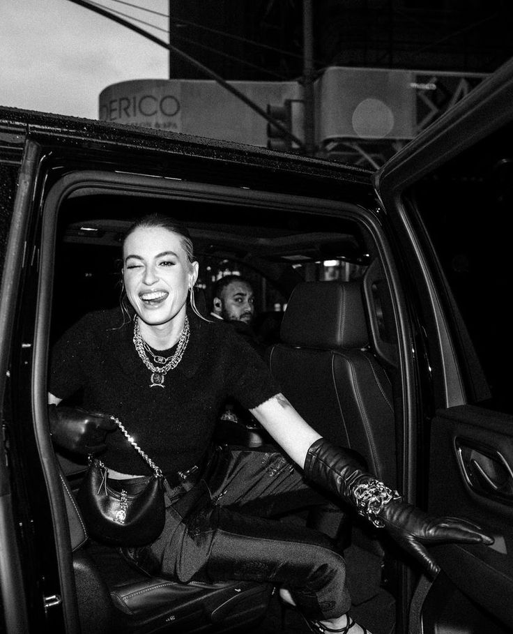 a black and white photo of a woman sitting in the driver's seat of a car