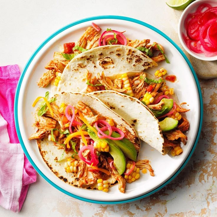 three tacos on a plate with corn and salsa