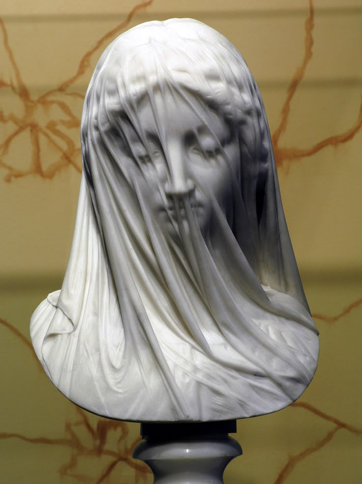 a white busturine with a veil on it's head is shown in front of a wall