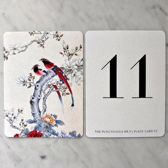 two cards with birds on them sitting next to each other in front of a marble table