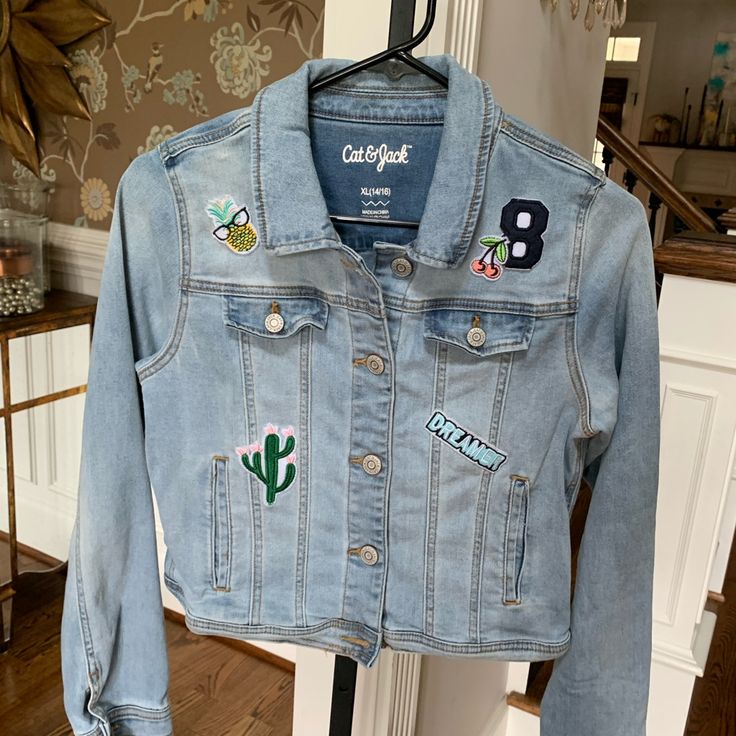 a denim jacket with patches on it hanging from a rack in front of a door