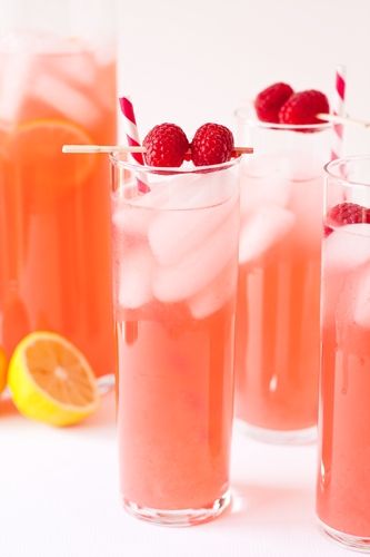 three glasses filled with raspberry lemonade punch and garnished with strawberries